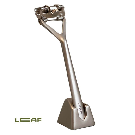 leaf pivoting head razor in stand - matt chrome. Tiled background with plant in distance