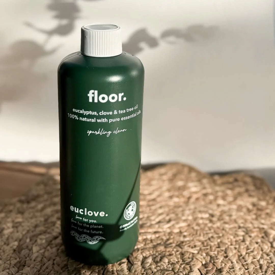 Green bottle labeled 'floor.' by euclove on a textured surface with a blurred natural background