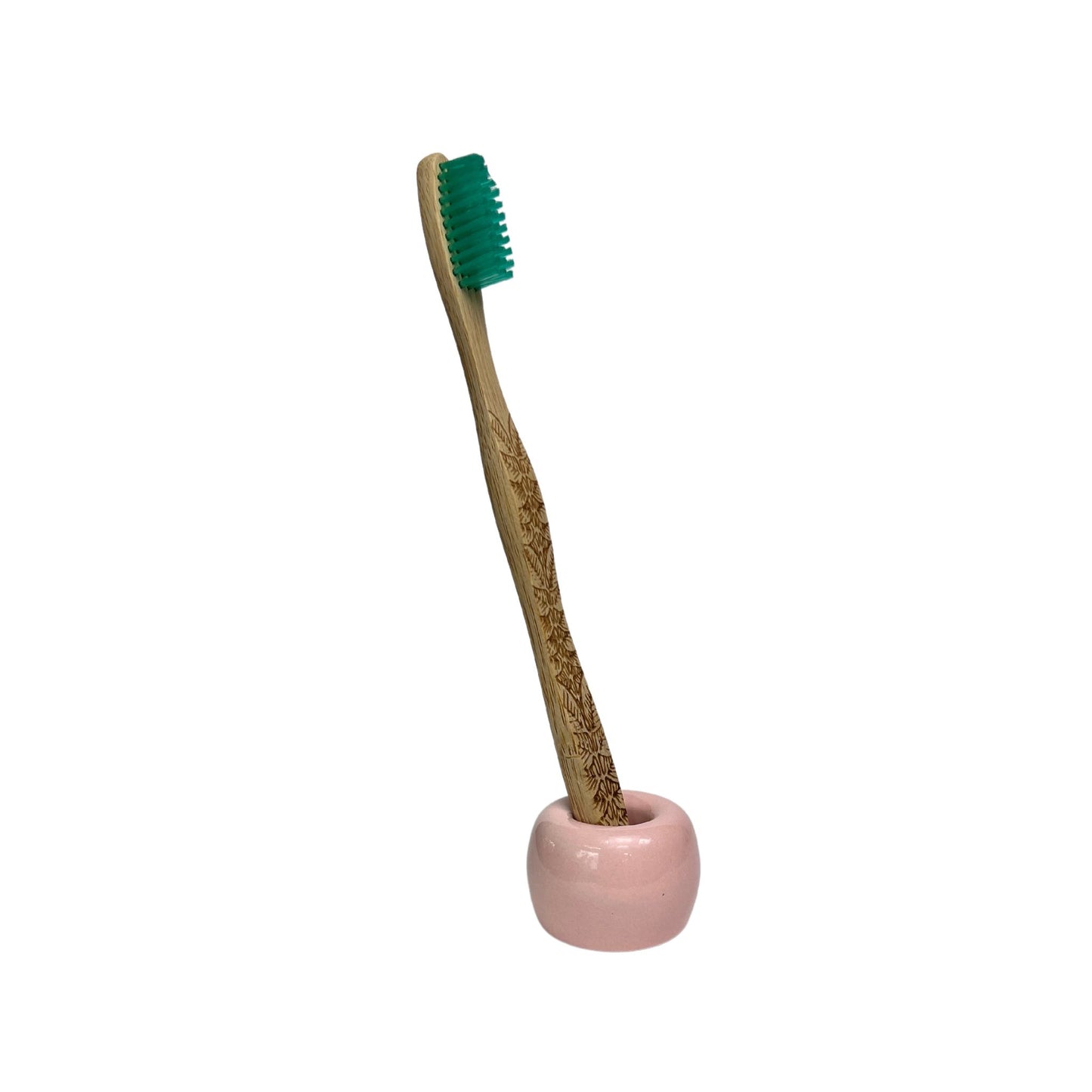 small ceramic toothbrush holder in glossy pink finish holding a bamboo toothbrush